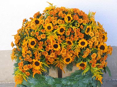 Trauerkranz mit orangenen Blumen und Tannenzweigen