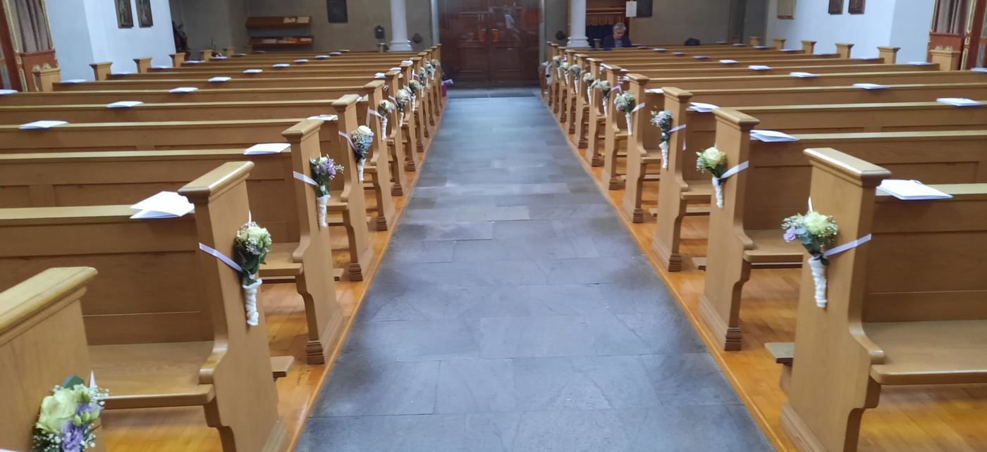 Mit Blumen geschmückte Kirchenbänke für eine Hochzeit